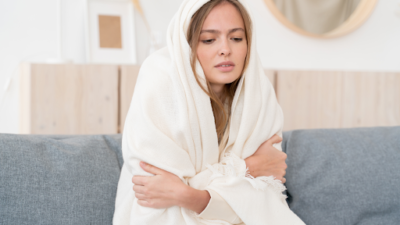 woman on couch wrapped in blanket and shivering