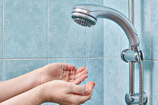 hands in water under shower head